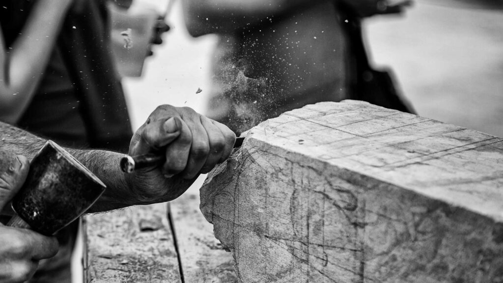 Hands using a hammer and chisel to break stone