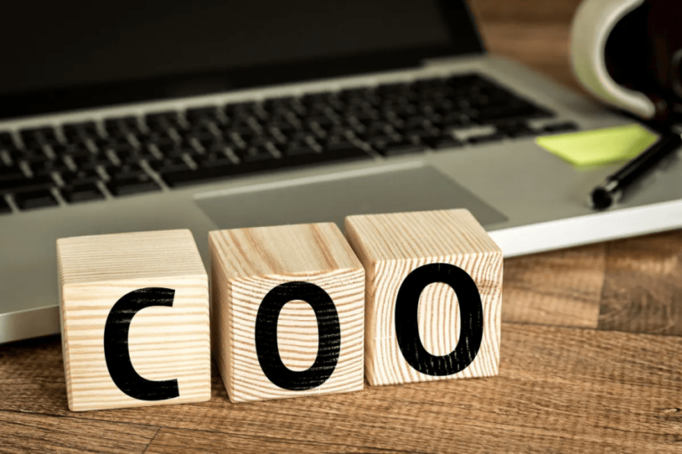 Letter blocks spelling COO in front of laptop